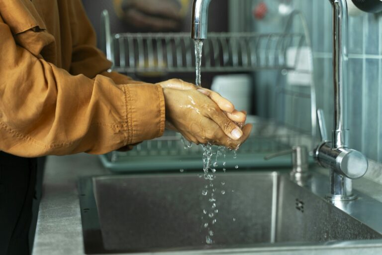 ?loseup of woman washing her hands before cooking at sink in kitchen. Hygiene concept
